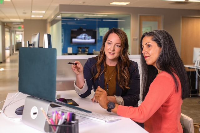 solarteure two women sitting at a desk looking at a computer screen